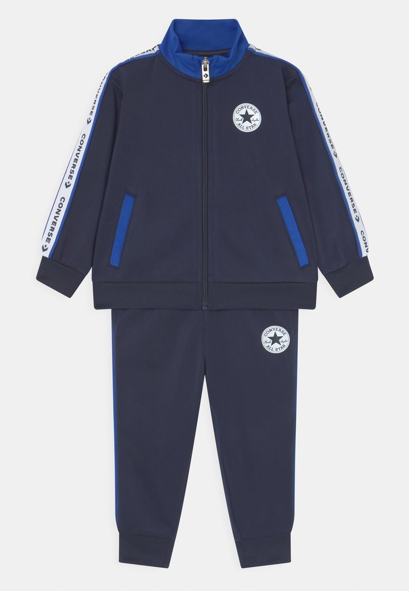 Chándal navy que incluye una chaqueta con cremallera y acentos en azul, bolsillos laterales y logo bordado. Puños y cintura elásticos para mayor comodidad.
