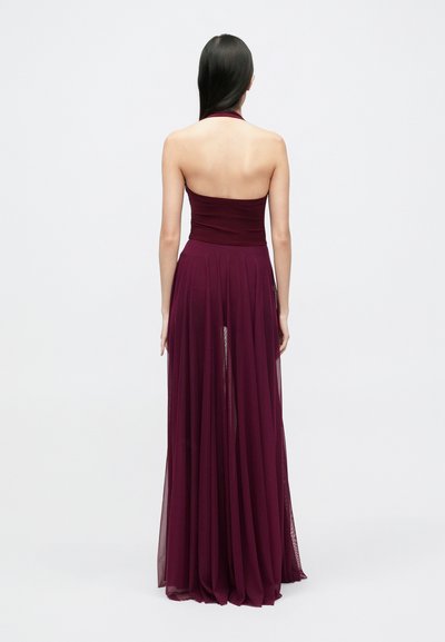 Rochie maxi burgundy cu decolteu halter, corsaj mulat și fustă vaporoasă transparentă. Textură moale a materialului, design formal și siluetă până la podea.