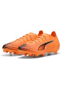 Scarpe da calcio arancioni brillanti con tomaia testurizzata, accenti neri sulla punta e sei tacchetti prominenti sulla suola per la trazione.