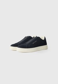 Adidași bleumarin din suede, cu un design tip slip-on, talpă din cauciuc crem în contrast și accente elastice pe partea superioară pentru o purtare ușoară.