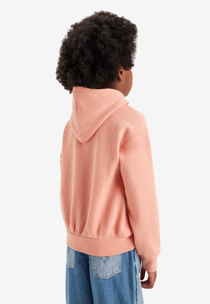 Roze hoodie van een zachte stof, met een aangesloten tailleband en geribbelde manchetten, gecombineerd met lichtblauwe distressed spijkerbroek.