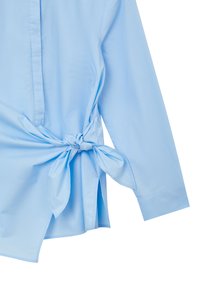 Himmelblaues, langärmliges Hemd mit einer Frontbindedetail, aus glattem Stoff gefertigt. Verfügt über einen Knopfverschluss und seitliche Schlitze.