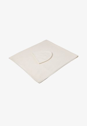 Coperta color crema con una consistenza morbida e angoli arrotondati. Presenta un cappuccio parzialmente visibile su un bordo, progettato per il comfort.