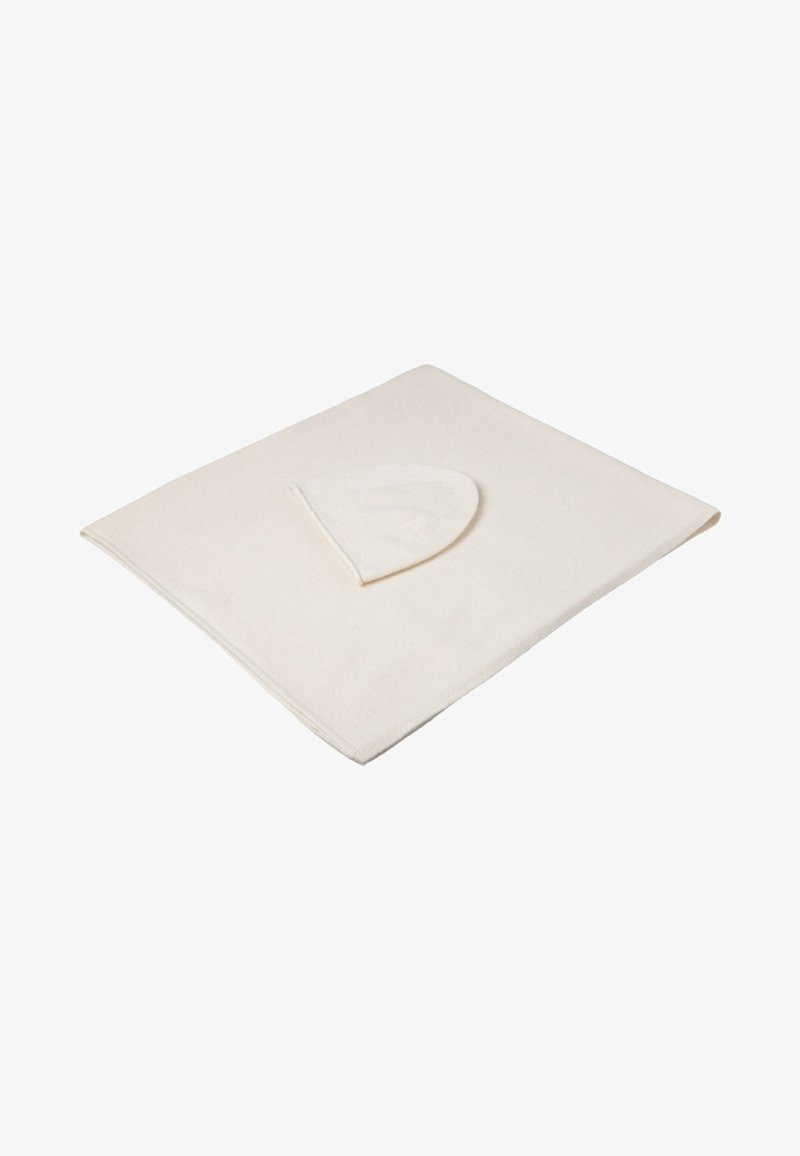 Crèmekleurige deken met een zachte textuur en ronde hoeken. Heeft een gedeeltelijk zichtbare capuchon aan één rand, ontworpen voor comfort.