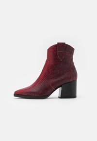 Bottines rouges à talon bloc avec un motif texturé en peau de serpent, bout pointu et un tirant à l'arrière pour un enfilage facile.