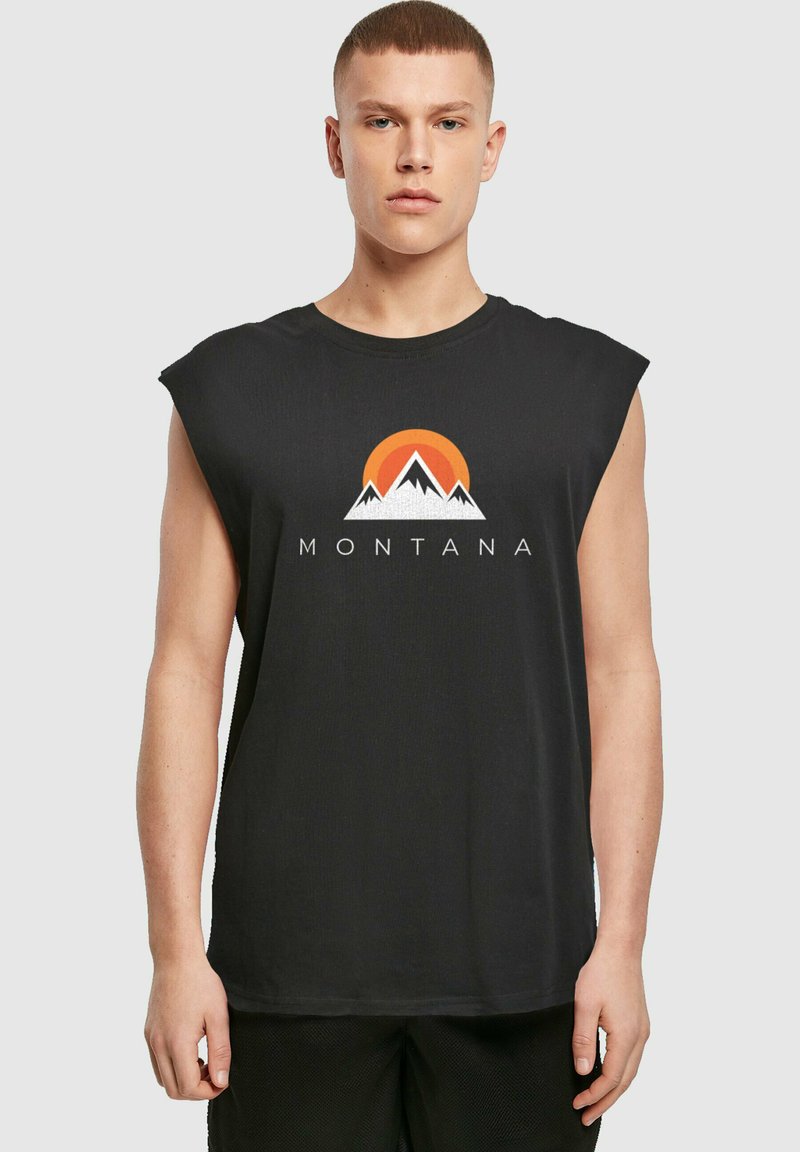T-shirt sans manches noir avec un graphisme de montagnes et d'un coucher de soleil, avec le texte "MONTANA" en dessous dans une police sans empattement en gras.