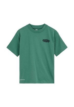 Žalia trumpomis rankovėmis suapvalintu kaklu marškinėliai su juodu „AIRGRD“ logotipu viršutinėje kairėje krūtinės pusėje ir mažais baltais užrašais prie apatinio krašto.