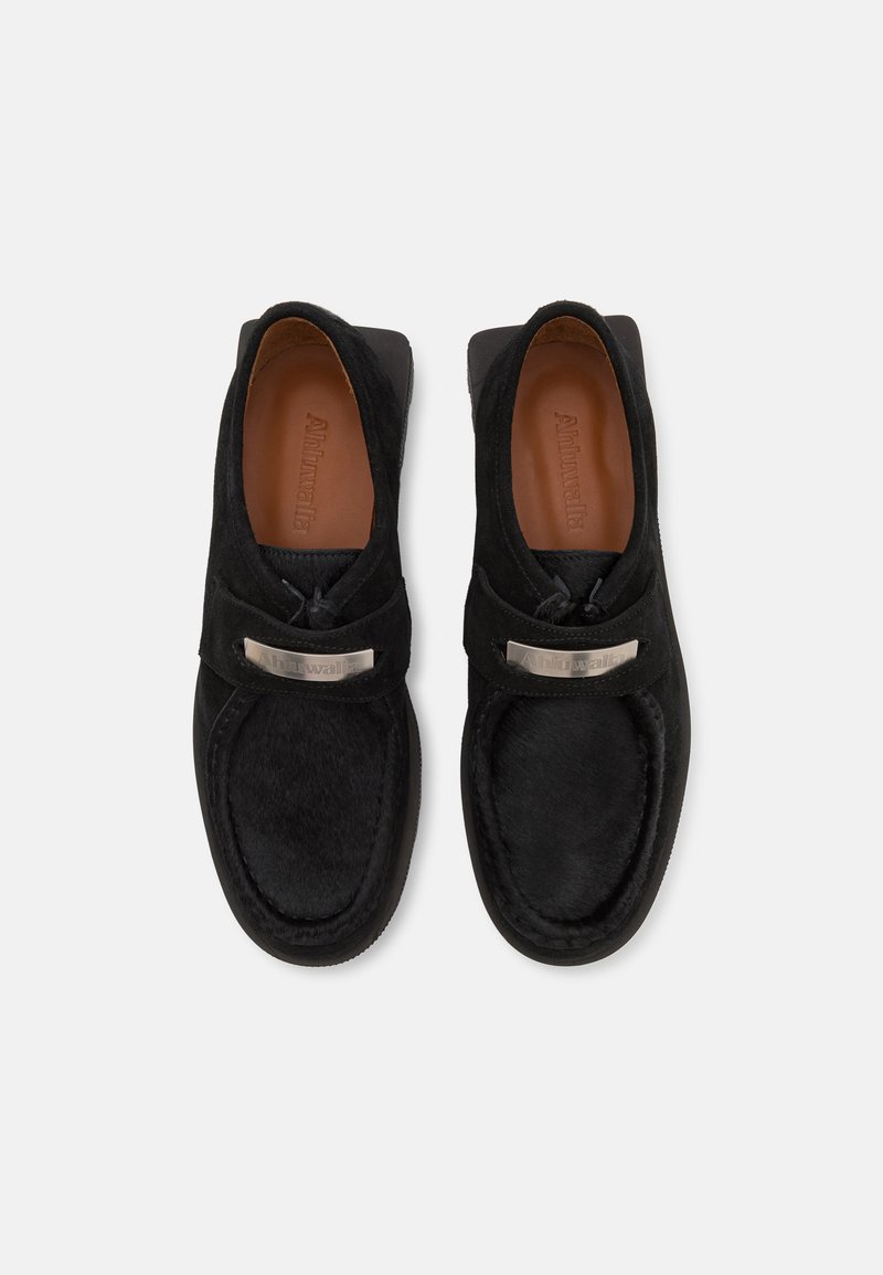 Des chaussures noires à enfiler en suede avec une texture lisse. Avec un accent métallique sur le dessus et une semelle cousue et rembourrée.
