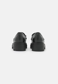 Zwarte leren schoenen met een stevige zool, met een gladde afwerking en zonder zichtbare hardware. Het ontwerp is eenvoudig en modern, met een weergave van de achterkant.