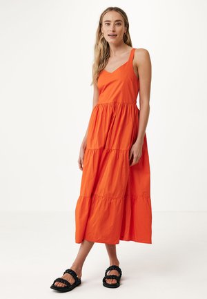 Orange, lagdelt maxi kjole lavet af let stof med et tætsiddende liv og tynde skulderstropper, parret med sorte flet-sandaler.