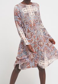 Robe à manches longues, longueur genou, ornée d'un motif paisley en bleu, marron et beige. Fabriquée en tissu léger avec une coupe décontractée.