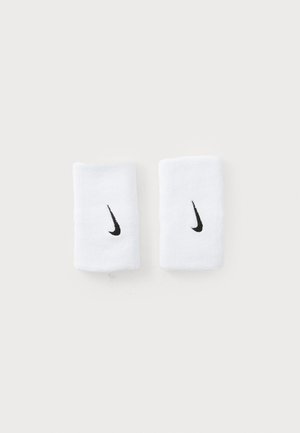 Balts Nike rokassprādzes pāris ar melniem Swoosh logo, novietotas blakus uz vienkrāsaina balta fona.
