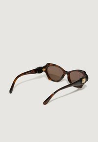 Óculos de sol em padrão tartaruga castanha com lentes redondas, adornados com um pequeno detalhe dourado na haste e braços pretos elegantes.