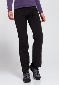 Svarta utomhusbyxor i lätt tyg, med dragkedjefickor och rak bendesign. I kombination med svarta vandringsskor.