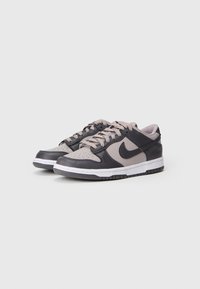 Sneakers Nike Dunk z ciemnoszarym skórzanym wierzchem, beżowymi akcentami, zaokrąglonym przodem, białą podeszwą międzyblokową oraz płaskimi sznurowadłami. Teksturowane z perforacjami.