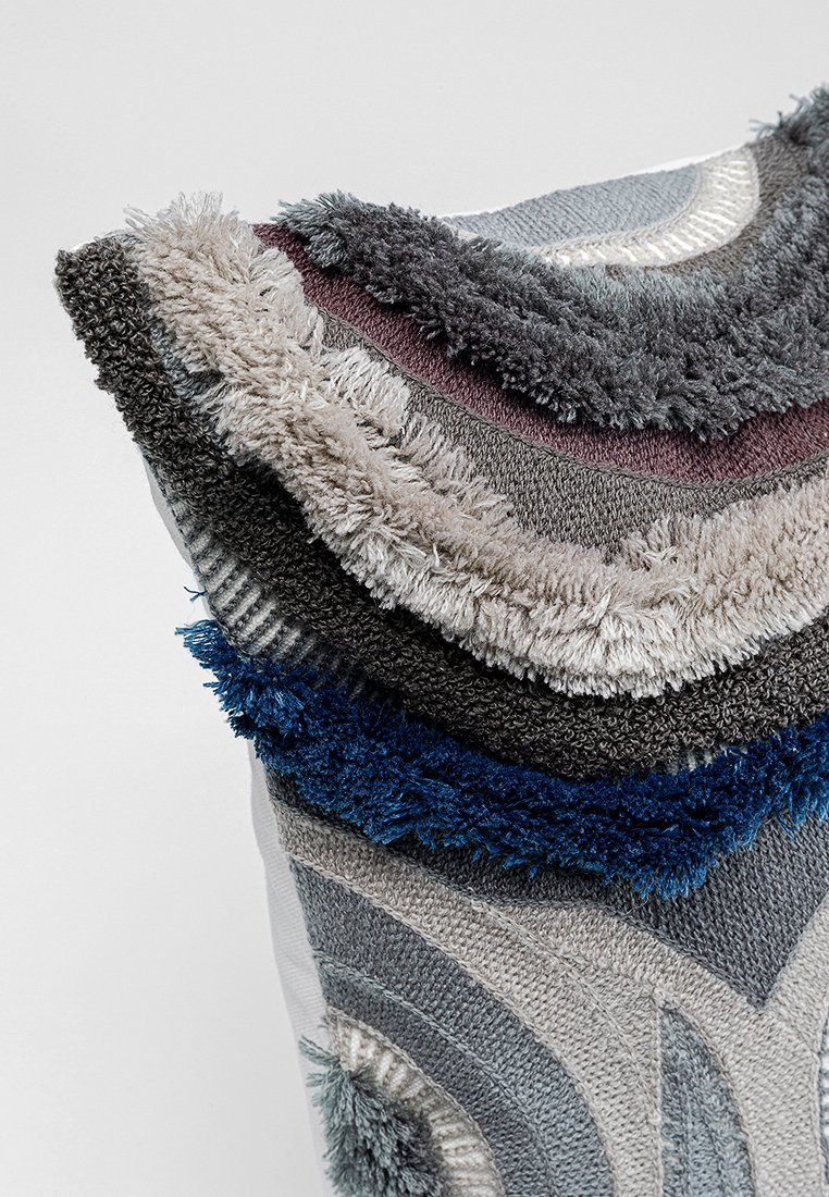 Texturiertem Gewebe in schichtweisen, geschwungenen Designs in Grautönen, Blau und Lila mit unterschiedlichen Florhöhen und Mustern. Weiches und plüschiges Aussehen.