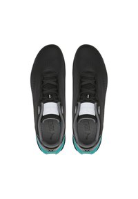 Baskets de sport noires avec une tige synthétique lisse, dotées d'une languette en mesh gris, de lacets noirs et d'accents teal sur le talon.
