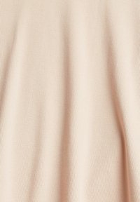 Světlé béžové žebrované látky s vertikálními pruhy, která vykazuje jemnou strukturu a hladký, rovnoměrný povrch.