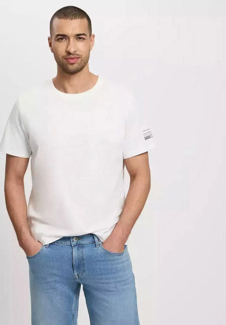 Biały bawełnowy T-shirt z okrągłym dekoltem i krótkimi rękawami. Ma małe paskowane logo na lewym rękawie. Nosi się go z jasnoniebieskimi dżinsami.