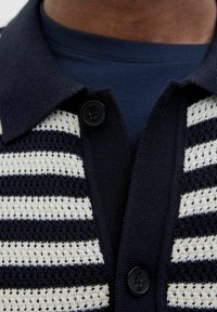 Jūras spēku un baltā svītrainā adītā žakete ar pogu aizdari, ar teksturētu rakstu un apkakles dizainu.