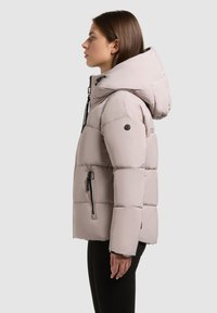 Lichtbeige gewatteerde jas met een capuchon, een doorgestikt ontwerp, verstelbare trekkoorden en ritszakken. Glad textuur met een moderne silhoutte.