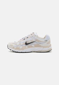 Scarpe da corsa leggere con tomaia in rete beige e bianca con accenti grigi, suola ammortizzata e suola esterna in gomma nera.