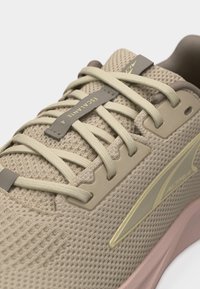 Μπεζ αθλητικό παπούτσι τρεξίματος με διχτυωτό υλικό, κορδόνια στο ίδιο χρώμα, ετικέτα "ESCALANTE 4" και μαλακή ροζ σόλα, σχεδιασμένο για αναπνευστικότητα και άνεση.