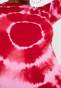 Camisa de tie-dye rojo y rosa con un patrón circular, con un escote redondo y mangas largas, hecha de una tela suave y ligera.