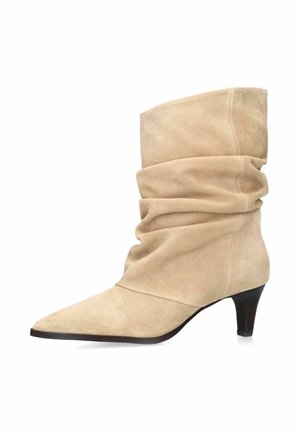 Beige suède slouchy mid-kuitlaars met puntige neus en korte zwarte kittenhak.