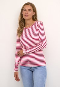 Rood-wit gestreept langemouwen shirt met een ronde hals en een klein hartembleem op de borst. De stof lijkt glad en licht van gewicht.
