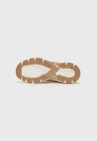 Suela de sneaker marrón claro con una superficie de goma texturizada, que presenta una plantilla acolchada y elementos de tracción con diseño.