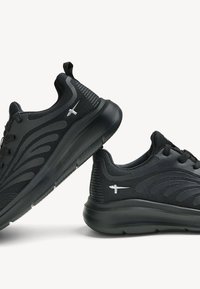 Ett par svarta sportskor med texturerade sulor, meshovre och syntetiska överdelar, samt en liten silverfärgad fågel-logotyp på sidorna mot en vit bakgrund.