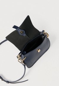 Tengerészkék bőrből készült kézitáska sima textúrával, aranyszínű fémrészletekkel és kontrasztos fekete velúr bélés belsővel. Nyitott fedeles kialakítás és állítható pánt.