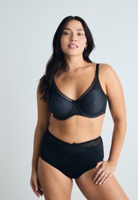 Schwarzes Wäsche-Set mit einem strukturierten BH mit Netzdetails und einem hochgeschnittenen Slip, beide aus einem glatten Stoff mit subtiler Textur.