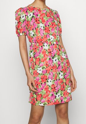 Woman wearing a knee-length dress with puff sleeves featuring bright red, pink, and green floral print on white background.