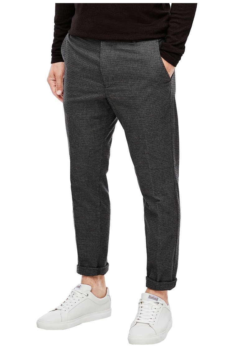 Šedé kalhoty s kostkovaným vzorem, bočními kapsami, manžetami a slim fit, kombinované s bílými teniskami. Hladká textilie.
