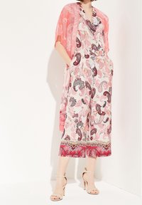 Mono multicolor con estampado de paisley, detalles en rosa y pernas anchas; combinado con una chaqueta transparente coral y tacones nude.