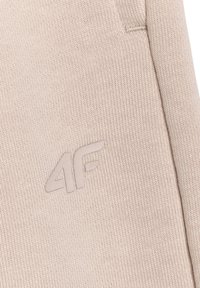 Tissu beige texturé avec couture cousue et logo 4F embossé de couleur assortie sur la surface du vêtement.