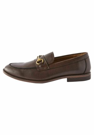 Mocassin en cuir marron présentant un bout arrondi, un talon plat et des accessoires en métal doré. Finition texturée avec des détails de couture.