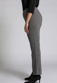 Grijze fitted broek gemaakt van gladde stof, met een middelhoge taille en taps toelopende benen, gecombineerd met zwarte puntige hakken.