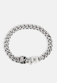 Zilveren metalen kettingarmband met grote schakels, een doodshoofdsluiting en gegraveerde details op de sluiting. Gladde textuur en glanzende afwerking.
