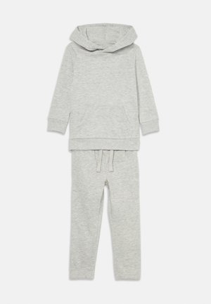 Grauer Hoodie mit einer Fronttasche und weitem Hals, kombiniert mit passenden Jogginghosen mit elastischem Bund und Kordelzug. Weiche Textur.