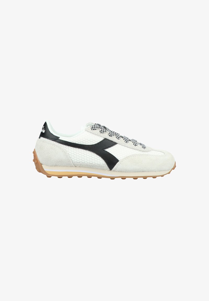 Witte mesh en suède sport schoenen met een zwart logo en strepen, gestructureerde zwarte veters en een gumrubberen zool met kleine nopjes.