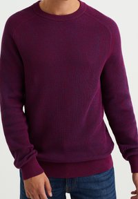 Suéter de punto acanalado púrpura con cuello redondo y mangas largas, que presenta una tela texturizada y una cintura ceñida. Corte casual.