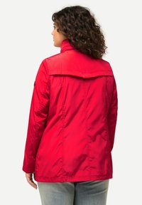Giacca rossa trapuntata con colletto alto e dettaglio sulla schiena. Caratterizzata da maniche lunghe e colore uniforme, realizzata in materiale sintetico leggero.
