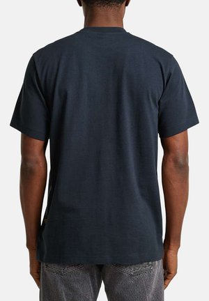 Mande iført en ensfarvet mørkeblå kortærmet T-shirt og slidte grå jeans, set bagfra mod en ensfarvet hvid baggrund.