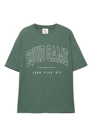 T-shirt en coton vert avec le texte "SQUID GAME" en lettres blanches en gras et "FOUR FIVE SIX" en dessous dans une police plus petite. Col ras du cou.