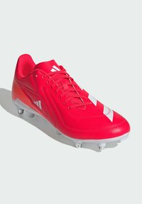 Scarpa da calcio rossa con superiore in sintetico liscio, caratterizzata da strisce bianche e una suola bianca con tacchetti visibili per la trazione.