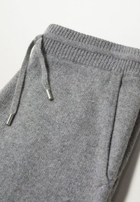 Grijze sweatpants met een geribde tailleband met een trekkoord en metalen uiteinden, gemaakt van een zachte, textuurstof.