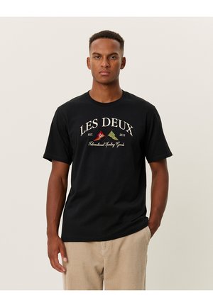 Camiseta de algodón negra con cuello redondo, que presenta un estampado gráfico en blanco y colorido que dice "LES DEUX" y "International Sporting Goods."